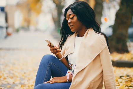 Black woman sitting in a autumn cityの写真素材