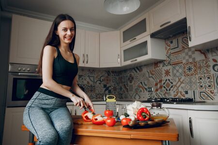 Sports girl in a kitchen with vegetablesの写真素材