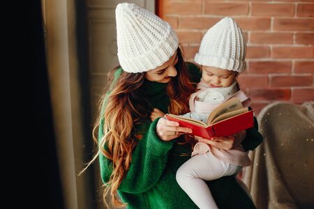 Stylish mother in a studio. Little girl in a knited hatの写真素材
