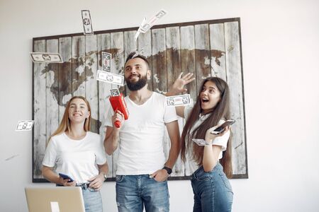 Young people have fun with money mashine in a office