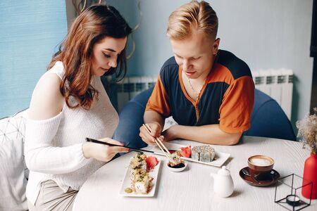 Couple sitting in a caffe and eating sushiの写真素材