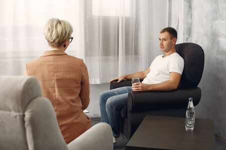 Man sitting in the psychologists office and talking about problemsの写真素材