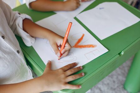 Children siting at the green table and drawingの写真素材