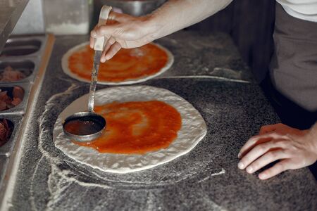 Chef in a white uniform prepare a pizzaa