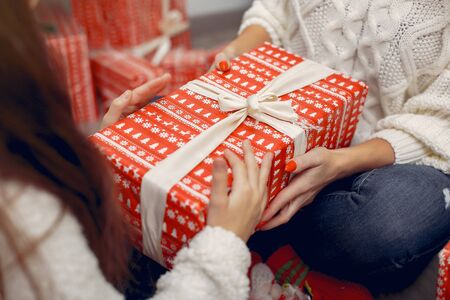 Beautiful mother in a white sweater. Family with cristmas gifts. Little girl in a santas hatの写真素材