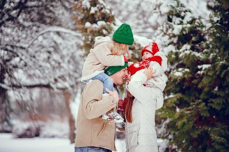 Beautiful mother in a red hat. Family playing in a winter park. Father with childrenの写真素材