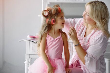 Mom and daughter at home with curlers on their headsの写真素材