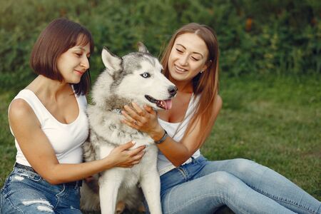 Two girls in a spring park playing with cute dogの写真素材