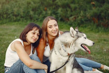 Two girls in a spring park playing with cute dogの写真素材