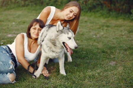 Two girls in a spring park playing with cute dogの写真素材