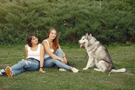 Two girls in a spring park playing with cute dogの写真素材