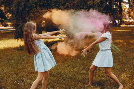 Beautiful girls with a colorful dry paints. Friends have fun in a summer parkの写真素材