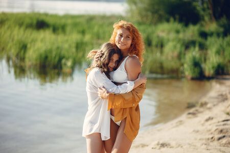 Sporty mother with cute daughter walking near lakeの写真素材
