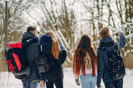 four young friends are walking in the winter snow-covered forest