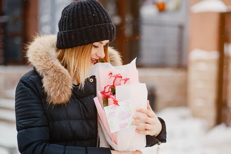 Fashion girl in a winter city. Lady in a black jacket . Woman standing near building with flowersの写真素材
