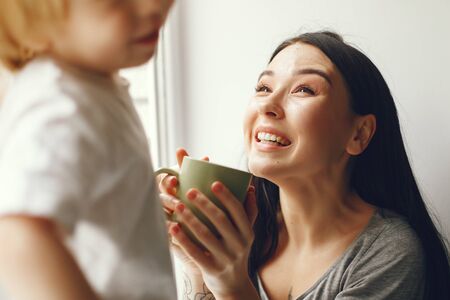 Mother and little son sitting on a windowsill with a teaの写真素材