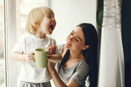 Mother and little son sitting on a windowsill with a teaの写真素材