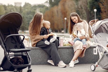 Two young mothers sitting in a autumn park with carriagesの写真素材