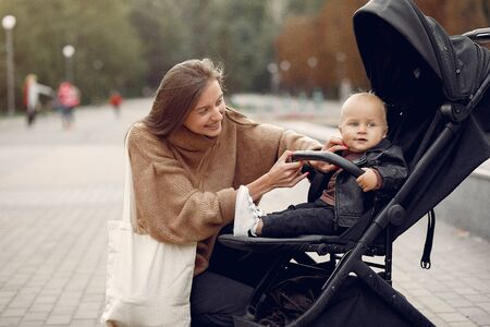 Young mother walking in a autumn park with carriageの写真素材