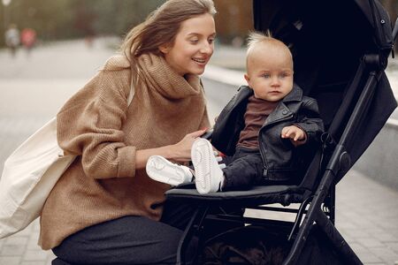 Young mother walking in a autumn park with carriage