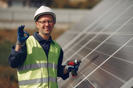 Man in a white helmet near a solar panel