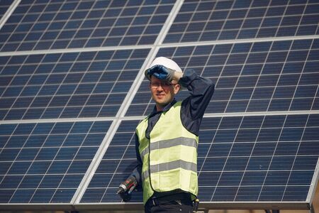 Man in a white helmet near a solar panel