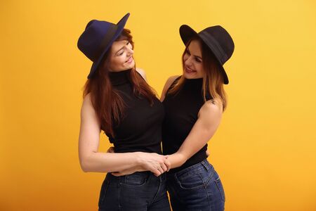 Fashion girls posing on a yellow backgroundの写真素材