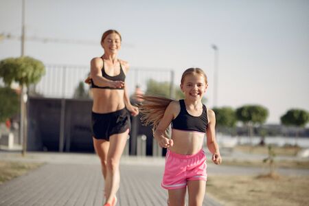 Mother with daughter doing sport in a summer parkの写真素材