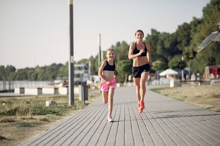 Mother with daughter doing sport in a summer parkの写真素材