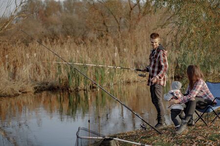 Family by the river. Guy in a red shirt. Father with little son in a fishing.