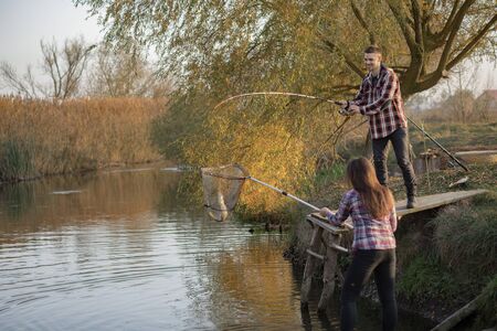 Couple by the river. Guy in a red shirt. Man in a fishing.の写真素材