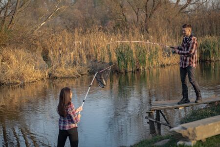 Couple by the river. Guy in a red shirt. Man in a fishing.