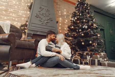 Beautiful couple sitting at home near christmas treeの写真素材