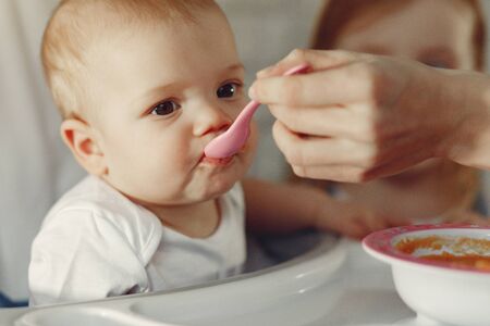 Mother feeds the little baby in a kitchen