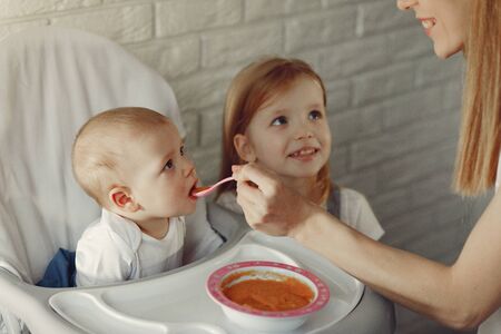 Mother feeds the little baby in a kitchenの写真素材