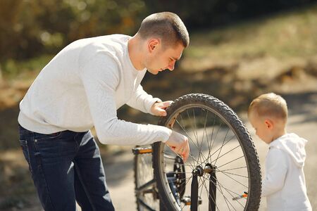 Family in a park. Father with son. People repare the bike.