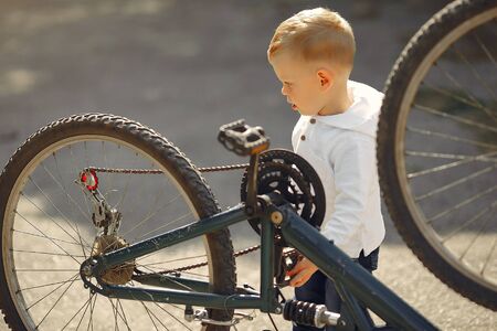 Child in a summer park. Boy fixing his bike. Kid with a bicycle.の写真素材
