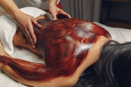 Massage doctor. The man make a masahe for woman. Procedures with chocolateの写真素材