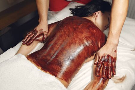 Massage doctor. The man make a masahe for woman. Procedures with chocolateの写真素材