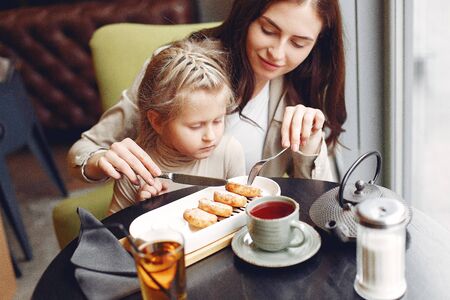 Mother with daughter sitting in a cafeの写真素材