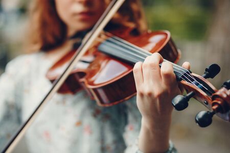 Beautiful girl in a summer park with a violinの写真素材