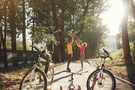 Family in a park. People with a bicycle. Parents with little daughter.の写真素材