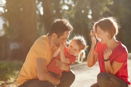 Family with cute little daughter. Father in a yellow t-shirt. People walks in a park.の写真素材