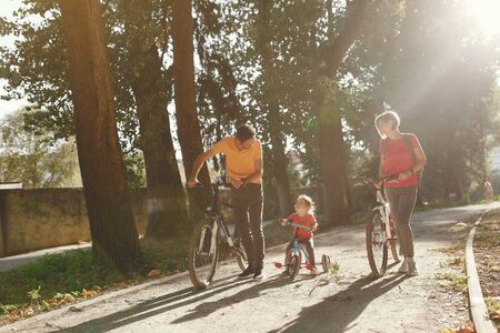 Family in a park. People with a bicycle. Parents with little daughter.の写真素材