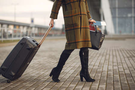 Woman with suitcase standing by the airportの写真素材