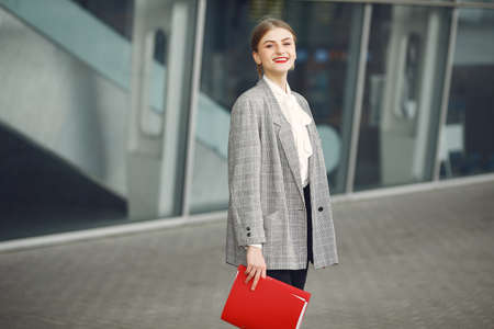 Woman standing in a city with a red folder