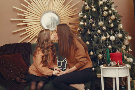 Mother with cute daughter near christmas tree