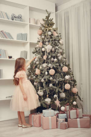Little girl near christmas tree in a pink dressの写真素材