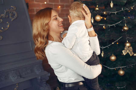 Mother with cute son at home near christmas treeの写真素材