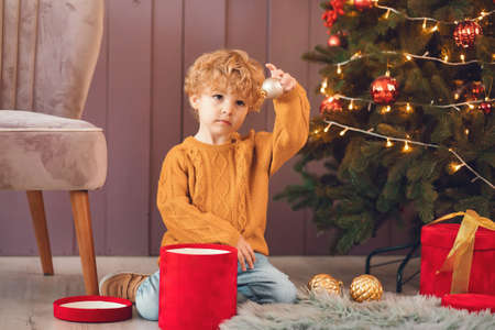 Little boy near christmas tree in a brown sweaterの写真素材